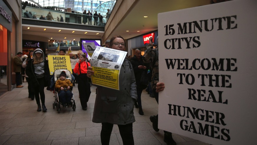 February 11, 2023, Leeds, West Yorkshire, United Kingdom: Protesters carry placards through the shopping mall warning of 15 minute cities and the covid-19 jab. Freedom campaigners march across the cit ...