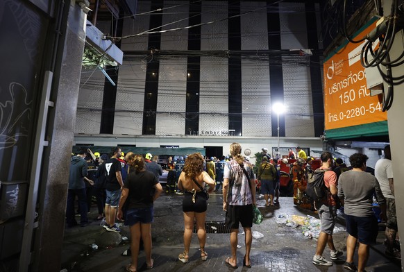 epa11797947 Tourists gather at the scene of a blaze at The Ember Hotel in Bangkok, Thailand, 29 December 2024. According to police at the scene, a number of casualties were reported when a fire broke  ...