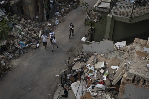 People walk next debris from destroyed buildings on a neighborhood near the site of last week&#039;s explosion that hit the seaport of Beirut, Lebanon, Thursday, Aug. 13, 2020. (AP Photo/Felipe Dana)