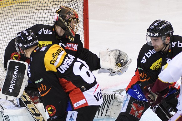 Bern Goalie Leonardo Genoni, Mitte, stoppt den Puck, an der Seite von Berns Ramon Untersander, links, und Berns Yanik Burrenm, rechts, im dritten Eishockey Playoff-Viertelfinalspiel der National Leagu ...