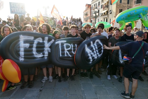 epa13117920 People chant slogans and hold inflatable devices during a protest against a visit by US Ambassador to Italy Tilman Fertitta in Venice, Italy, 17 July 2026. Local activist groups organized  ...