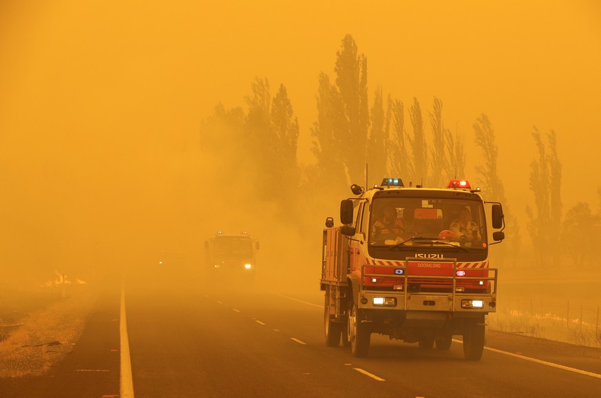 Fire burns in the grass along the road as firetrucks pass by near Bumbalong, south of the Australian capital, Canberra, Saturday, Feb. 1, 2020. The threat is posed by a blaze on Canberra&#039;s southe ...