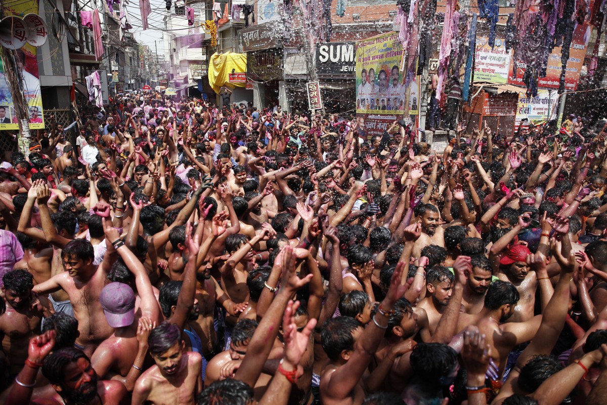 FILE - In this March 29, 2021, file photo, Indians, their faces smeared with color and glitter, dance as water is sprinkled on them during Holi celebrations in Prayagraj, India. India���s death toll f ...