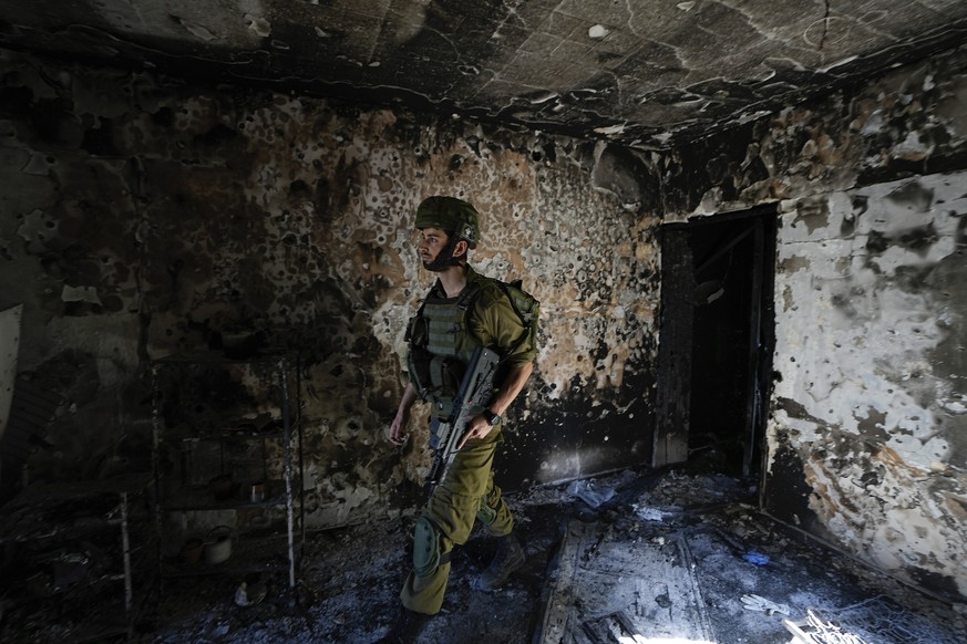 An Israeli soldier inspects a house damaged by Hamas militants in Kibbutz Kfar Azza, Israel, Wednesday, October 8.  On October 18, 2023, the kibbutz was overrun by Hamas militants from the nearby Gaza Strip.  7, ...