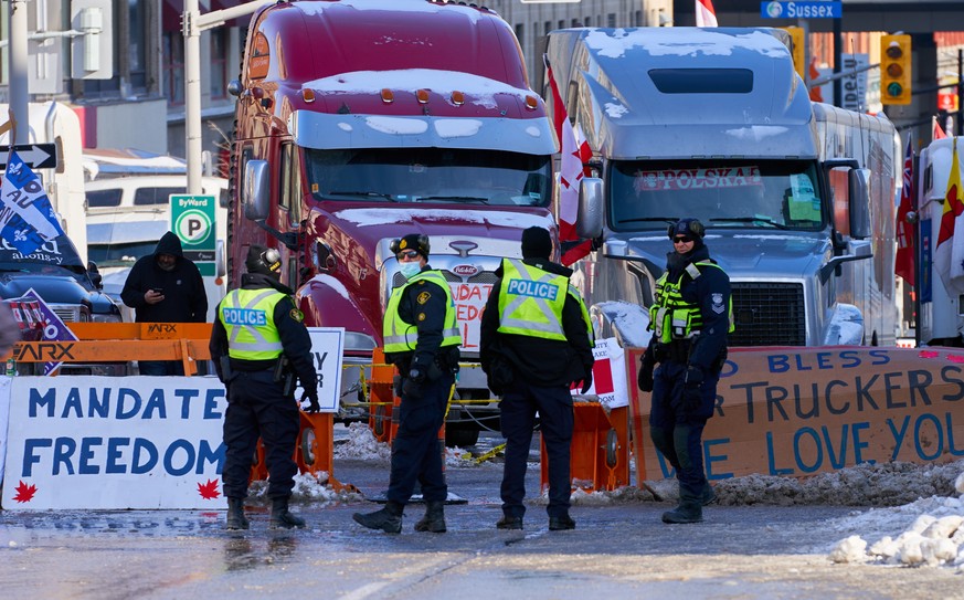 epa09736438 Policemen stand near the truckers sit-in, after the mayor of Ottawa has declared a state of emergency in the Canadian capital after a 10-day-long protest by truck drivers over Covid-19 res ...