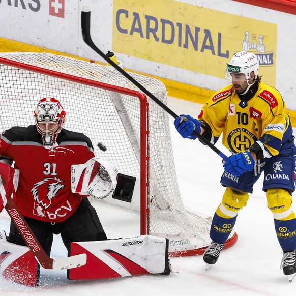The goaltender Connor Hughes (LHC), left, turns away the puck past Andres Ambuehl (HCD), right, during the fifth leg of the National League regular season game of the Swiss Championship between Lausan ...