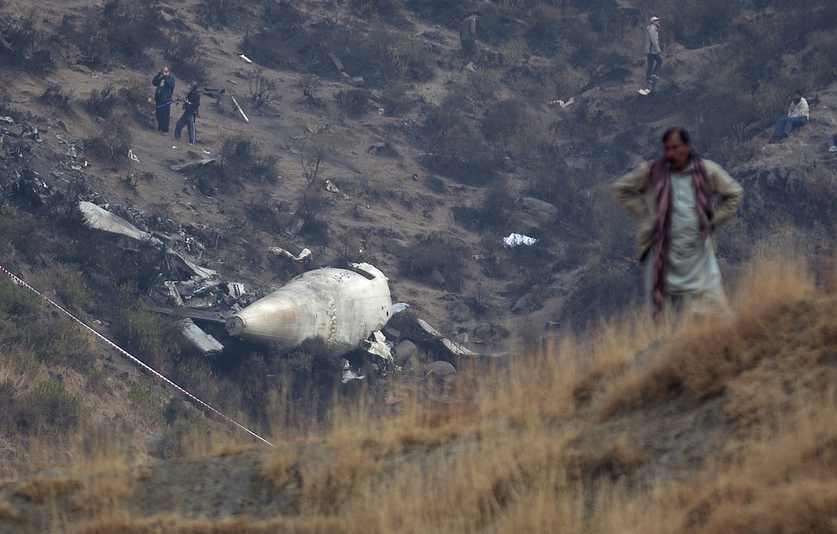CORRECTS NAME OF THE VILLAGE - A Pakistan villager stands at the site of plane crash as investigation is in progress in Gug near Havelian, Pakistan, Thursday, Dec. 8, 2016. Pakistan's national ca ...