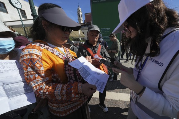 Stewards check tourists&#039; QR codes outside the main train station in Venice, Italy, Friday, April 18, 2025, as the city for a second year is charging day-trippers an arrivals tax. (AP Photo/Antoni ...