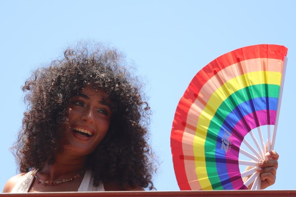 epa13032660 A participant holding a hand fan takes part in a march along the beachfront promenade during the Tel Aviv Pride Parade in Tel Aviv, Israel, 12 June 2026. Attracting tens of thousands of pa ...