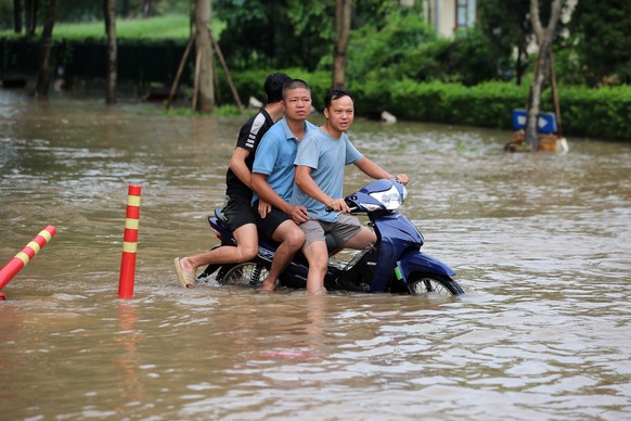 epa12418742 Three men ride a motorbike through a flooded street in Hanoi, Vietnam, 01 October 2025. According to state media, Typhoon Bualoi has caused flooding and landslides in Vietnam and left at l ...