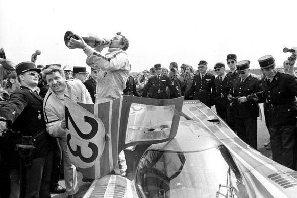 Hans Herrmann stands on the floor of the winning Salzburg 917k as he celebrates with champagne after his victory in the 24 Hours Le Mans car race with his teammate Richard Attwood, not shown, in Paris ...