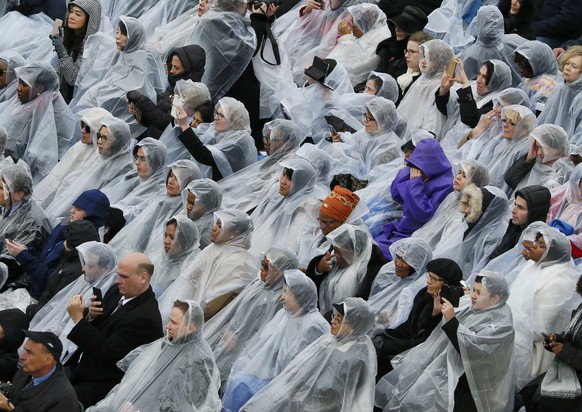 Attendees sit in the rain as U.S. President Donald Trump delivers his speech at the inauguration ceremonies on the West front of the U.S. Capitol in Washington, U.S., January 20, 2017. REUTERS/Rick Wi ...