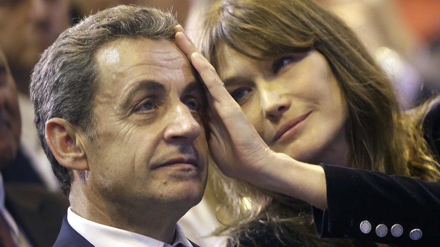 FILE - In this Thursday, Oct. 27, 2016 file picture, Carla Bruni-Sarkozy caresses the brow of her husband, the former French President and candidate for France&#039;s conservative presidential primary ...