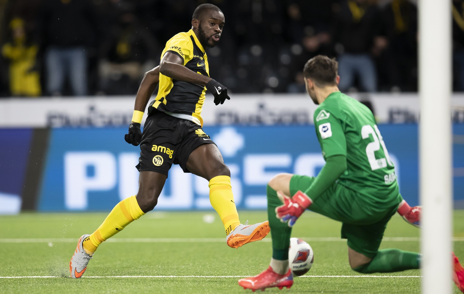 YBs Wilfried Kanga erzielt das Tor zum 2-1 gegen Luganos Torhueter Amir Saipi im Super League Spiel zwischen dem BSC Young Boys Bern und dem FC Lugano, am Mittwoch 1. Dezember 2021 im Stadion Wankdorf ...