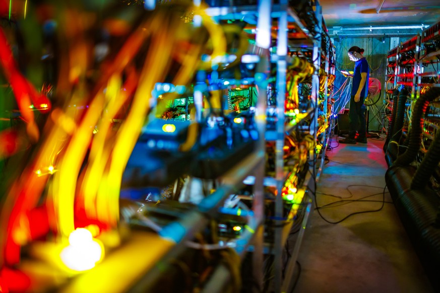 Alpine Mining co founder Theo Martinet is lit by the LED status lights of electronic boards during a long exposure photograph at a cryptocurrency mine in the small alpine village of Gondo, Switzerland ...