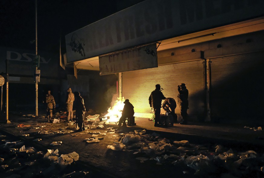 South African Defence Force soldiers keep themselves warm around a fire while stationed in Alexandra Township, near Johannesburg, to assist police in quelling looting and rioting Tuesday, July 13, 202 ...