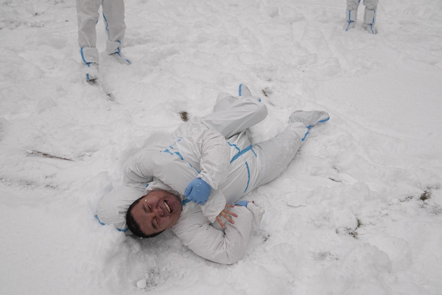 Two hotel workers in protective gear jokingly wrestle in the snow-covered courtyard of Shangri-La Beijing at the 2022 Winter Olympics, Sunday, Feb. 13, 2022, in Beijing. (AP Photo/Jae C. Hong)