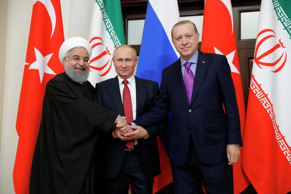 epa06344114 Russian President Vladimir Putin (C), Iranian President Hassan Rouhani (L) and Turkish President Recep Tayyip Erdogan (R) shake hands during their meeting in the Black sea resort of Sochi, ...