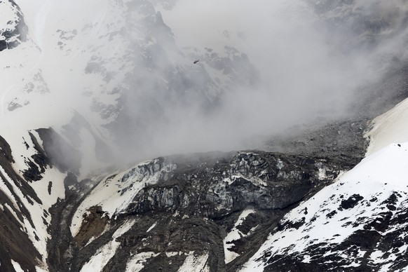 Ein Helikopter fliegt ueber den mit Felsen und Geroell von einem Felssturz bedeckten Nestgletscher, an einer Flanke des Berges Bietschhorn im Loetschental, am Montag, 19. Mai 2025, aufgenommen auf ein ...