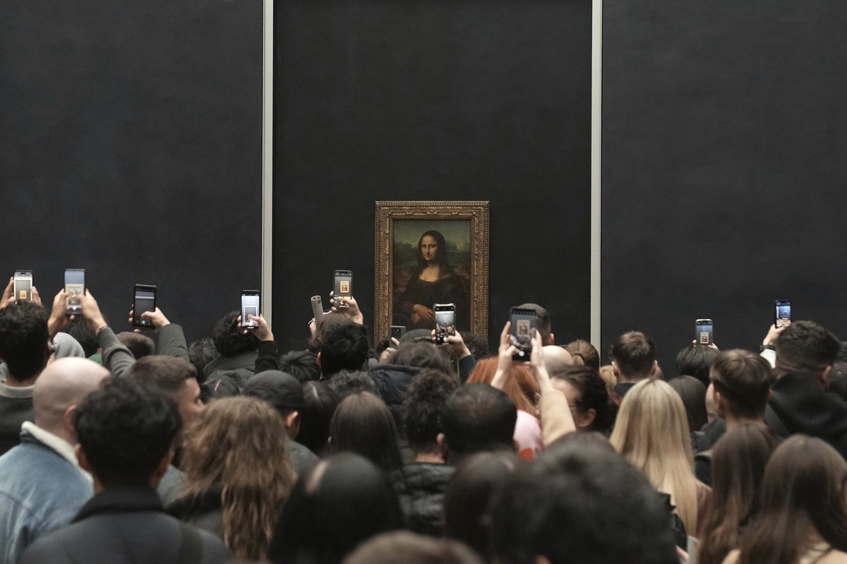 Visitors take photographs from their mobile phone of Leonardo da Vinci's painting of the Mona Lisa, at the Louvre museum, Monday, Jan. 27, 2025 in Paris. (AP Photo/Thibault Camus)