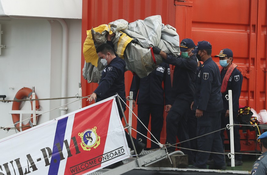 Rescuers carry debris found in the waters around the location where a Sriwijaya Air passenger jet has lost contact with air traffic controllers shortly after the takeoff, at the search and rescue comm ...