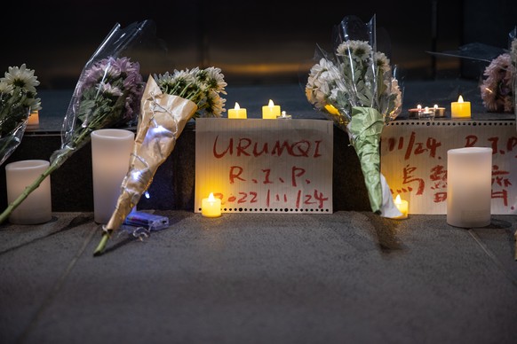 epa10334246 Flowers are left by mourners during a vigil for the victims of China���s zero-COVID policy and the victims of the Urumqi fire in Hong Kong, China, 28 November 2022. Protests against China& ...