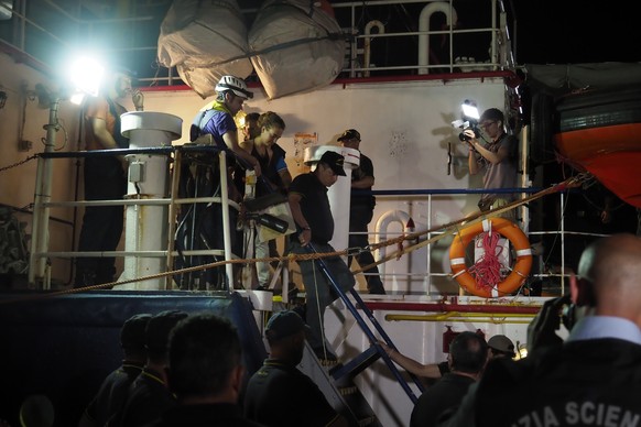 epa07682744 A handout photo made available by Sea-Watch shows Sea Watch 3 captain Carola Rackete (C) being arrested after entering the port of Lampedusa and ramming a patrol boat, in Lampedusa, Italy, ...