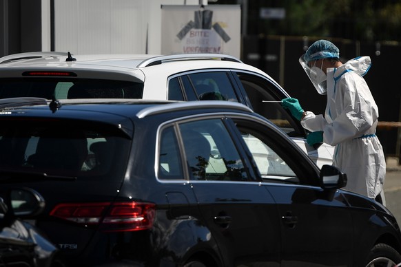 epa08612433 A health worker collects samples at a COVID-19 test station in Hochfelln, Germany, 19 August 2020. The test stations installed by Bavaria?s State Government near border crossings, at airpo ...