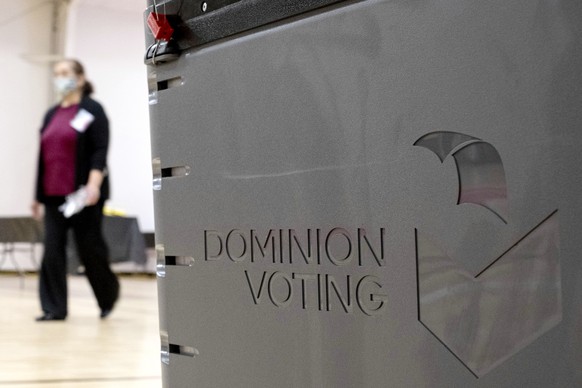 FILE - A worker passes a Dominion Voting ballot scanner while setting up a polling location at an elementary school in Gwinnett County, Ga., outside of Atlanta on Jan. 4, 2021. (AP Photo/Ben Gray, Fil ...