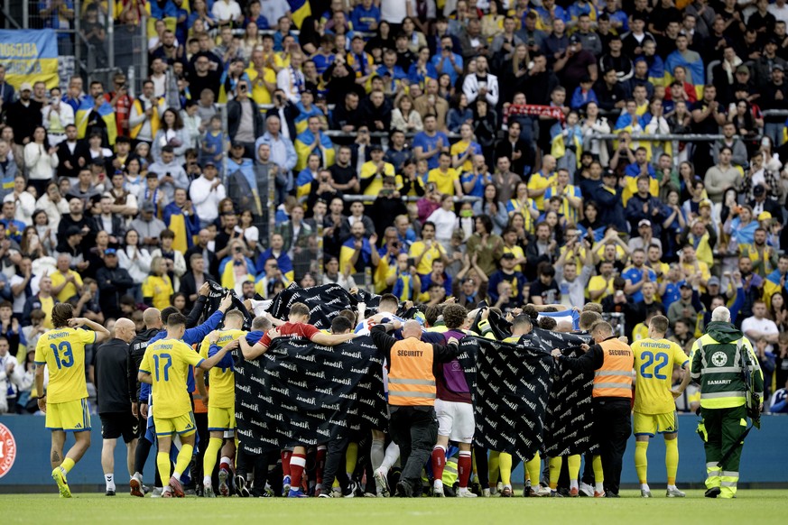epa13022979 Denmark's and Ukraine's players accompany Danish player Christian Eriksen to a waiting ambulance during the international soccer friendly match Denmark against Ukraine at Odense  ...