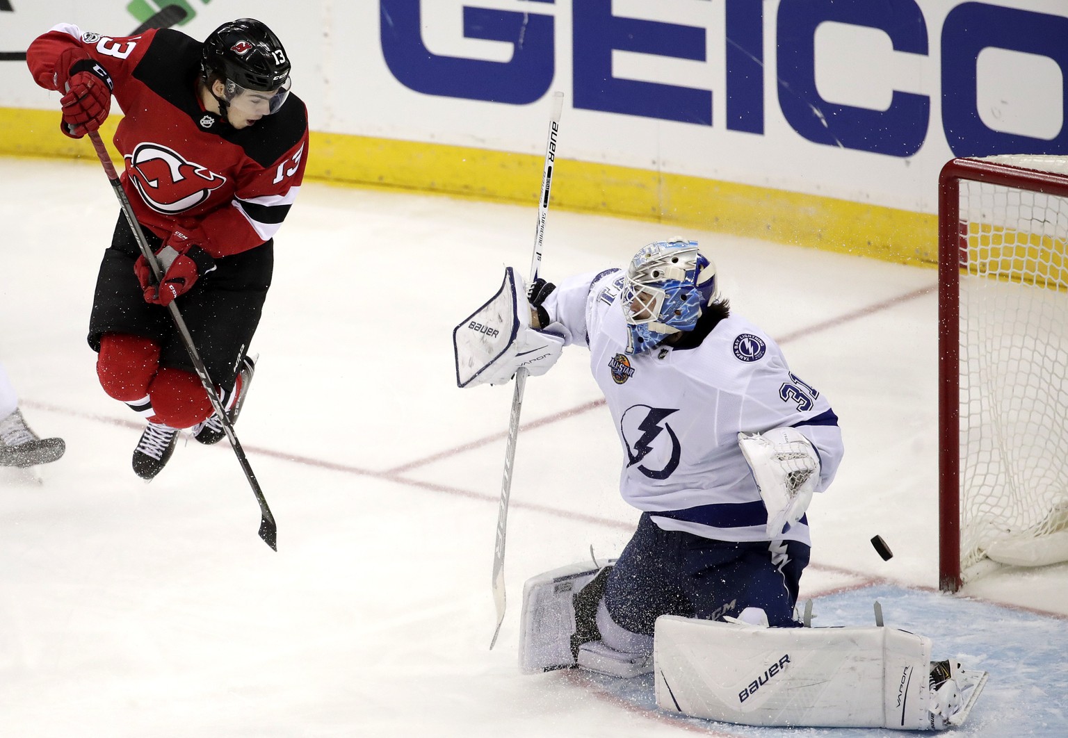 New Jersey Devils center Nico Hischier, left, of Switzerland, jumps out to screen a shot from a teammate as Tampa Bay Lightning goalie Peter Budaj, of Slovakia, (31) deflects the shot during the third ...