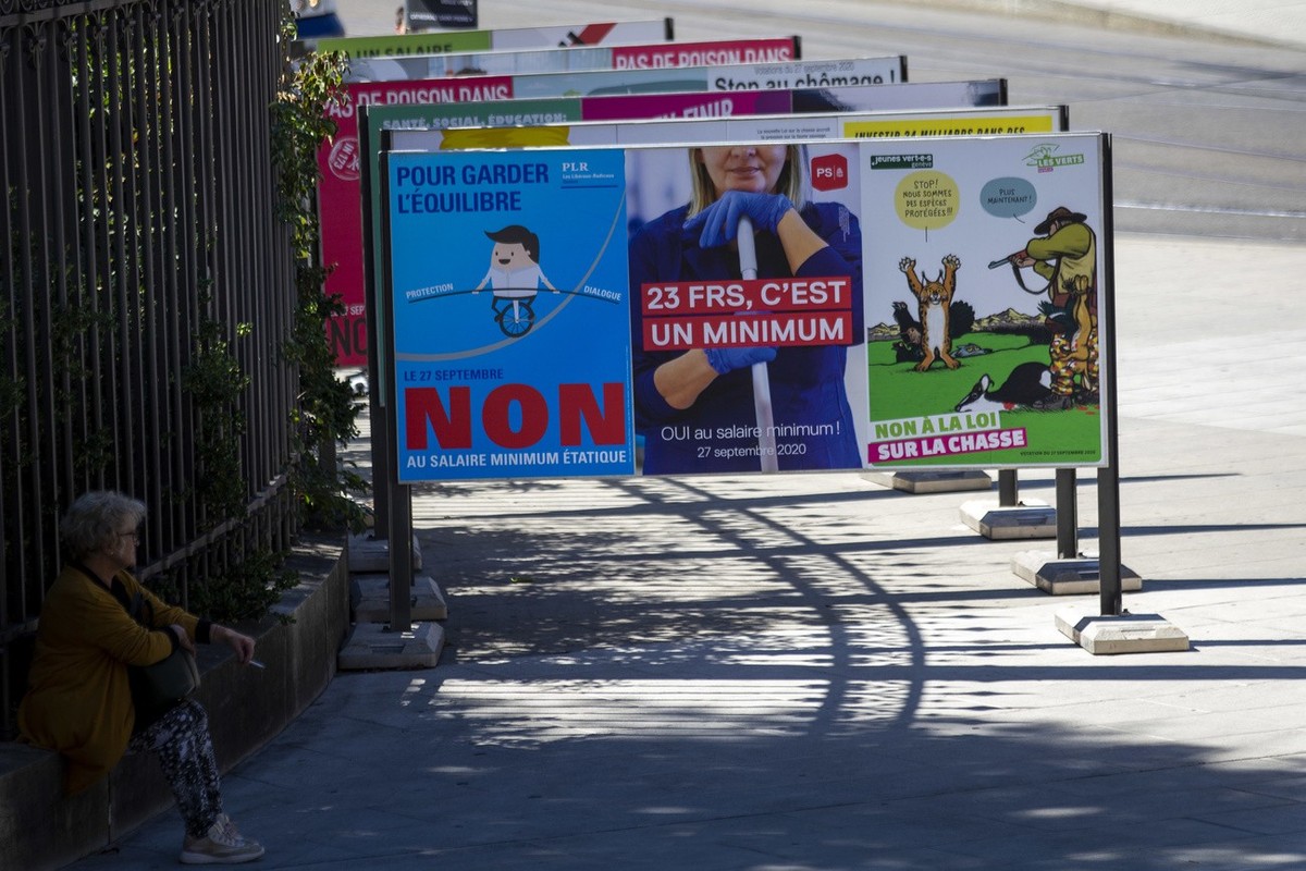 Une femme est assise vers les affiches des partis politiques et des associations donnant leurs mots d'ordre pour les votations populaires federales et cantonales du 27 septembre, ce mercredi 2 se ...