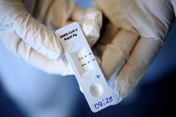 A health worker shows a positive SARS-CoV-2 Rapid Antigen Test from the Swiss multinational healthcare company Roche just after collecting a nose swab sample for a polymerase chain reaction (PCR) at t ...