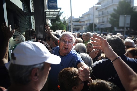 epa04825961 Pensioners who do not own ATM cards line up outside a bank branch to withdraw part of their pensions as a result of capital controls imposed by the Greek government, in Peristeri suburb we ...