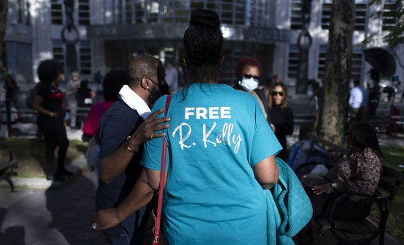 epa09492129 Fans of singer R. Kelly gather outside of the United States Federal Courthouse, in the background, where Kelly was found guilty on multiple charges of racketeering and sex trafficking in t ...