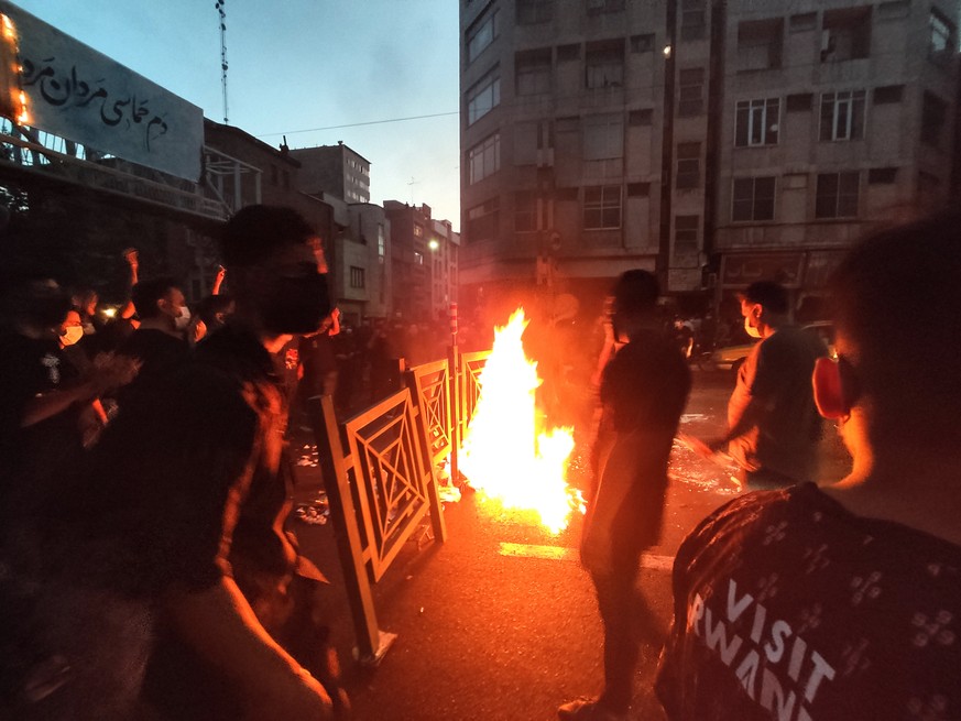 In this Wednesday, Sept. 21, 2022, photo taken by an individual not employed by the Associated Press and obtained by the AP outside Iran, protesters make fire and block the street during a protest ove ...