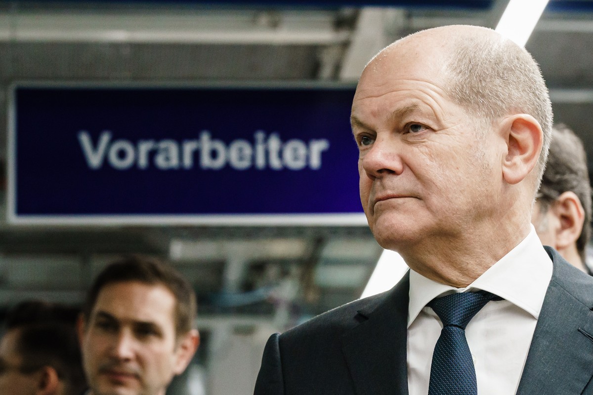 epa10373825 German Chancellor Olaf Scholz (R) looks on in front of a sign reading 'Vorarbeiter' (German for: foreman) in a conversation with workers during a visit to the BMW Group motorcycl ...