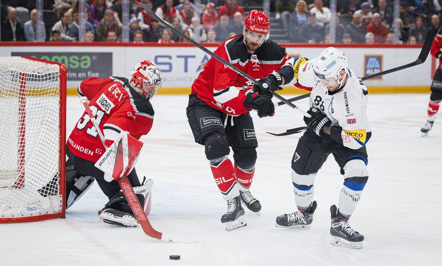 L&#039;attaquant lausannois Cody Almond, centre, lutte pour le puck avec l&#039;attaquant du fribourg Christopher DiDomenico, droite, lors de l&#039;acte 4 des demi-finales des play-off du championnat ...