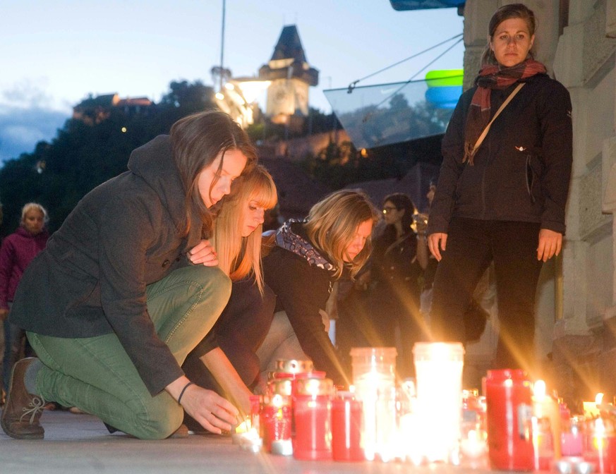 epa04811516 People light candles in tribute to the victims, at the site where a SUV drove into pedestrians in the city center of Graz, Austria, 20 June 2015. According to reports, a man drove his SUV  ...