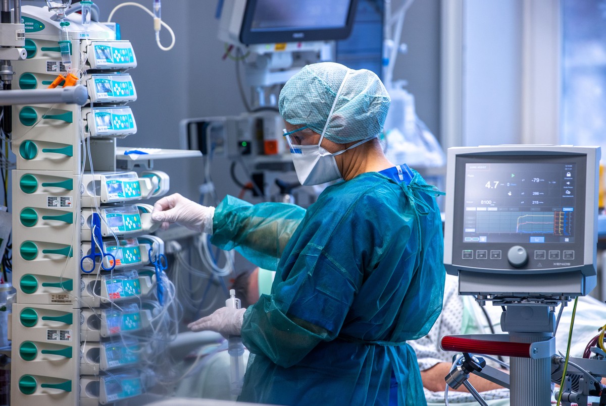 ARCHIV - 30.11.2021, Mecklenburg-Vorpommern, Rostock: �rzte und Pflegekr�fte betreuen Patienten in einem der Behandlungszimmer der Intensivstation in der Universit�tsmedizin Rostock im Jahr 2021. Die  ...