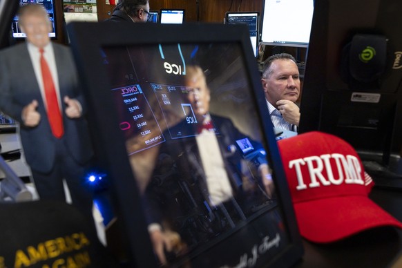 epa11930470 A trader works with an assembly of US President Donald Trump paraphernalia sen in the foreground on the floor of the New York Stock Exchange in New York, New York, USA, 28 February 2025. E ...