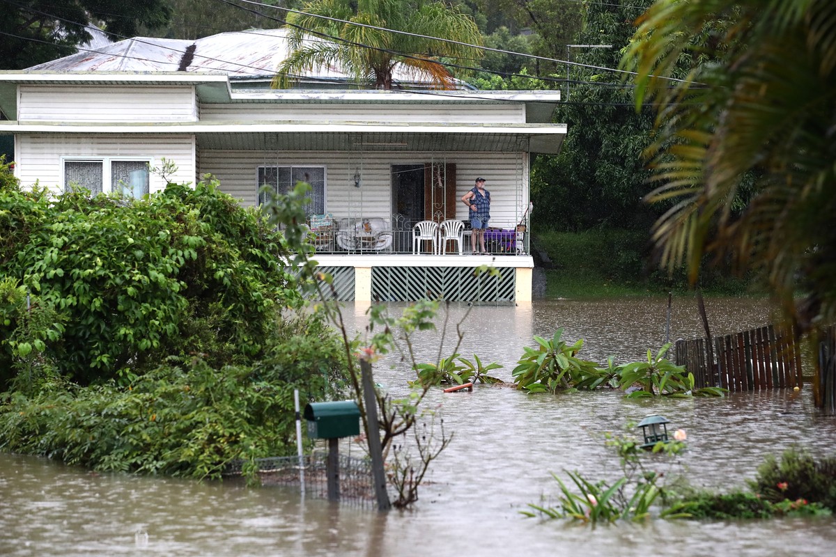 epa09785595 A resident watches floodwaters from his house in Ipswich, Australia, 26 February 2022. Southeast Queensland residents are facing more intense rain and life-threatening flash floods as one  ...
