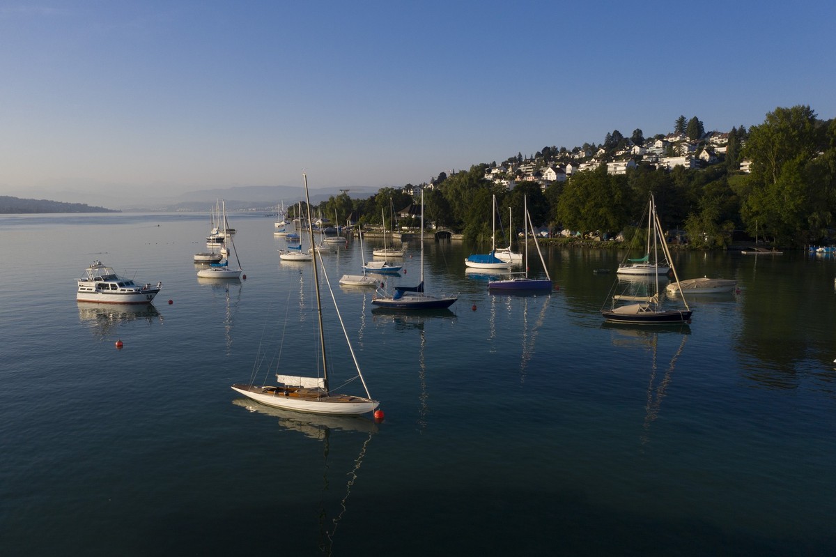 Anchored sailing boats on Lake Zuerich in Wollishofen, in the background residential houses in Kilchberg, Switzerland, on the morning of July 23, 2019. (KEYSTONE/Christian Beutler)

Geankerte Segelboo ...