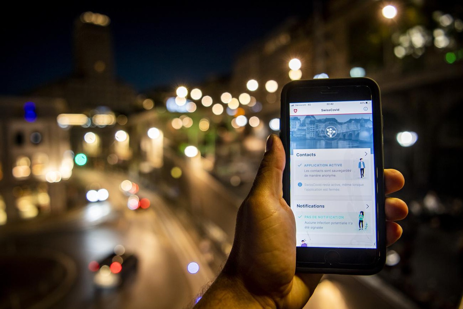 Une personne regarde sur son smartphone l&#039;application SwissCovid alors que des personnes font la fete lors d&#039;une soiree d&#039;ete le samedi 27 juin 2020 dans le quartier du Flon a Lausanne. ...