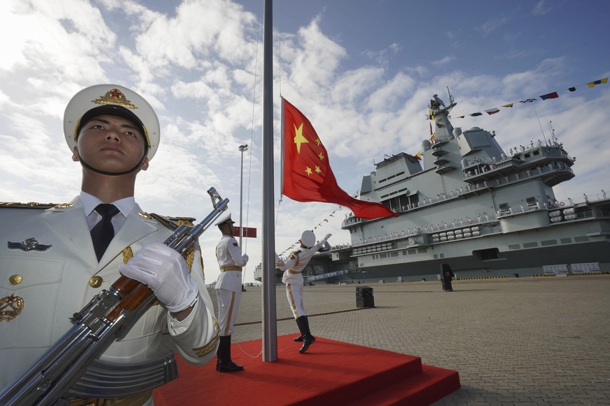 FILE - In this file photo taken Dec. 17, 2019 and released Dec. 27, 2019 by Xinhua News Agency, Chinese honor guard raise the Chinese flag during the commissioning ceremony of China's Shandong aircraf ...