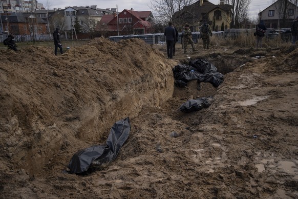 Journalists stand by a mass grave in Bucha, on the outskirts of Kyiv, Ukraine, Monday, April 4, 2022. Russia is facing a fresh wave of condemnation after evidence emerged of what appeared to be delibe ...