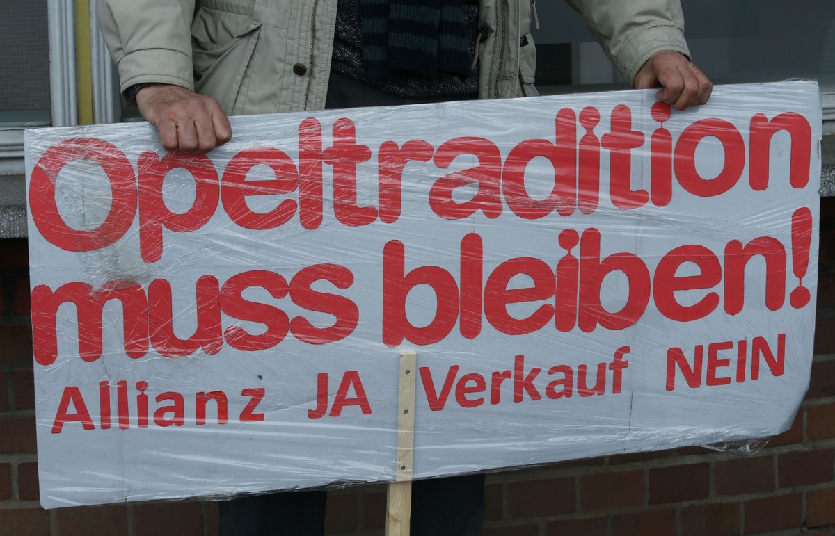 A man with a self-made placard that reads 'Opel tradition must remain - alliance yes - sale no' protests against a deal by General Motors to sell the carmaker to France's PSA Group in f ...