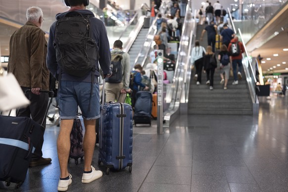 Passagiere gehen mit Koffer, Taschen oder Rucksaecken zum Ferienbeginn durch die Hallen zu den Check-In-Schaltern, aufgenommen am Samstag, 13. Juli 2024 auf dem Flughafen in Kloten. (KEYSTONE/Ennio Le ...