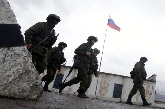 epa04113222 Armed men in military uniform march outside the territory of a Ukrainian military unit in the village of Perevalnoye, outside Simferopol, Ukraine, 07 March 2014. The Crimea's parlimen ...
