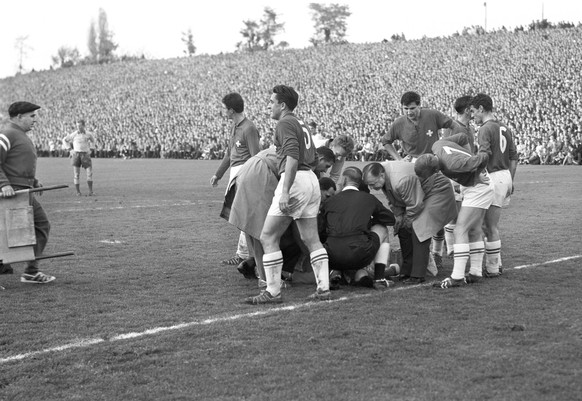 Mannschaftsaerzte, Mitspieler und Funktionaere kuemmern sich um den Schweizer Goalie Karl "Charly" Elsener, der waehrend des Qualifikationsspiels fuer die Weltmeisterschaft 1962 in Chile geg ...